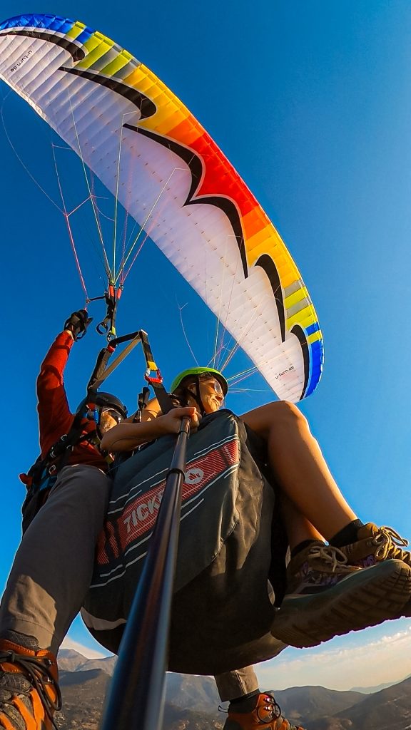 Woman on a paragliding tour with a rainbow parachute above