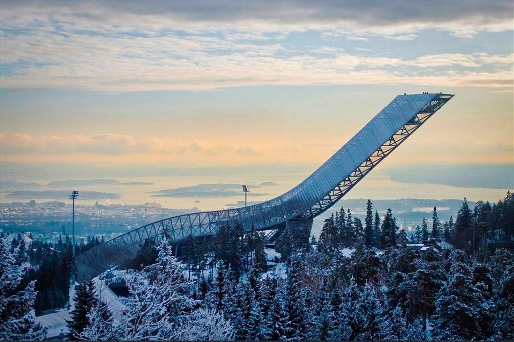 Holmenkollen Ski Museum surrounded by snow covered trees at sunset