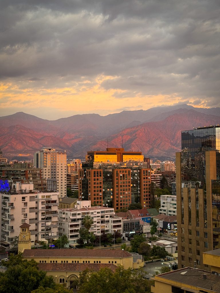 Glowing red mountains behind Santiago Chile skyscrapers at sunset