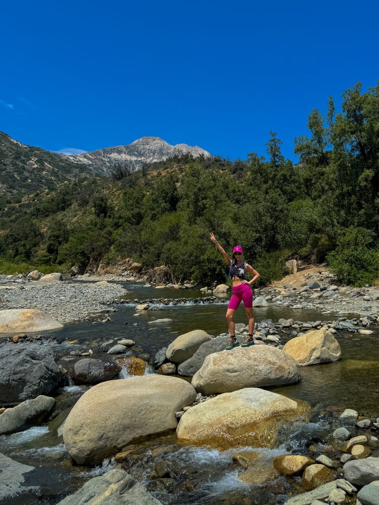 Woman standing on the giant boulders in the river at Parque Nacional Rio Clarillo