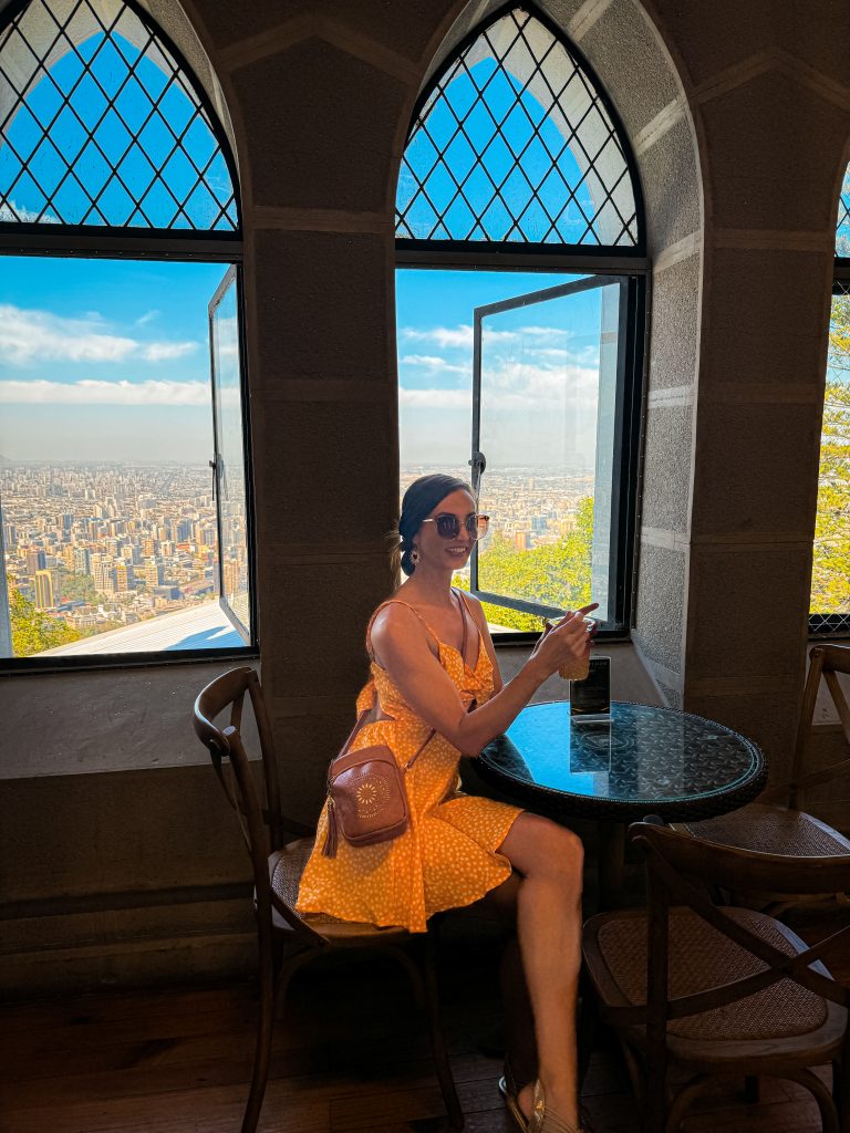 Woman enjoying a beverage the the view from Café Tudor on top of San Cristobal Hill 