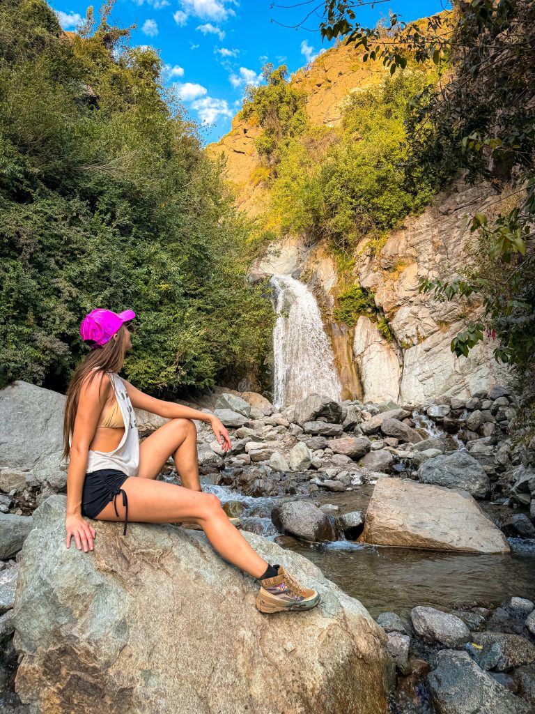 A woman sitting on a rock looking at a waterfall at Quebrada de Macúl
