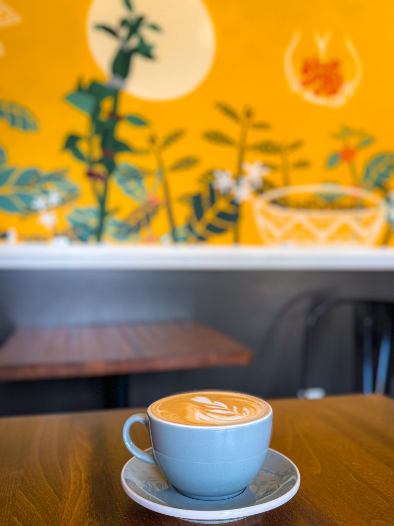 Hot latte in mug in front of colorful mural