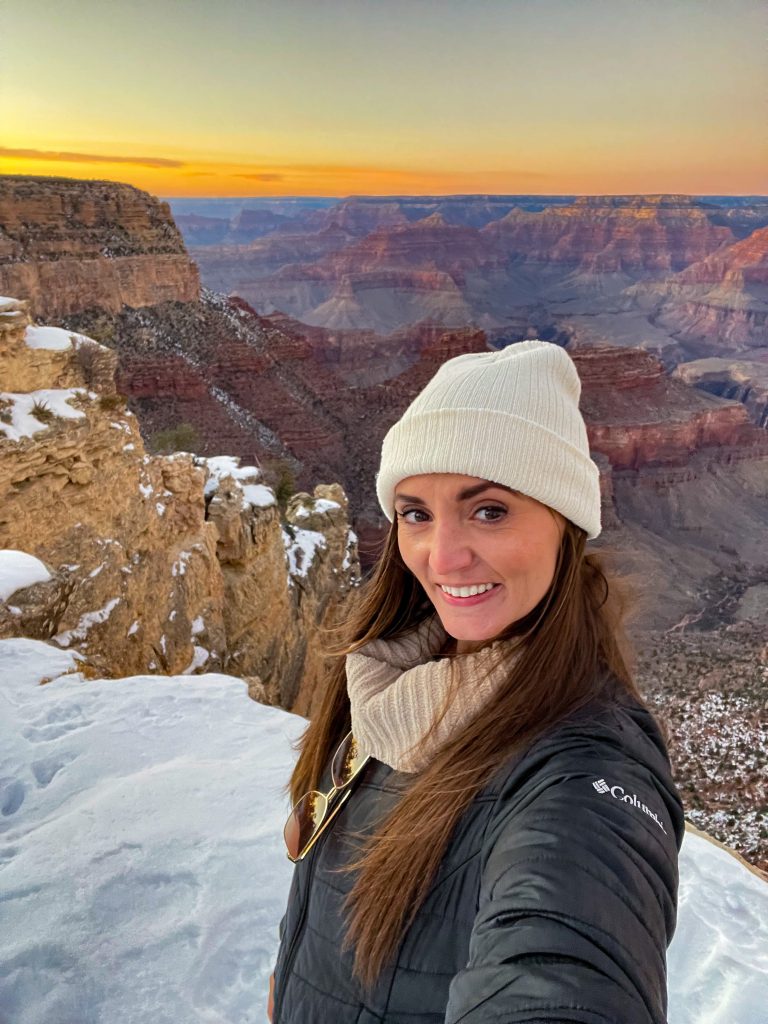 Woman in front of snow covered Grand Canyon at sunset