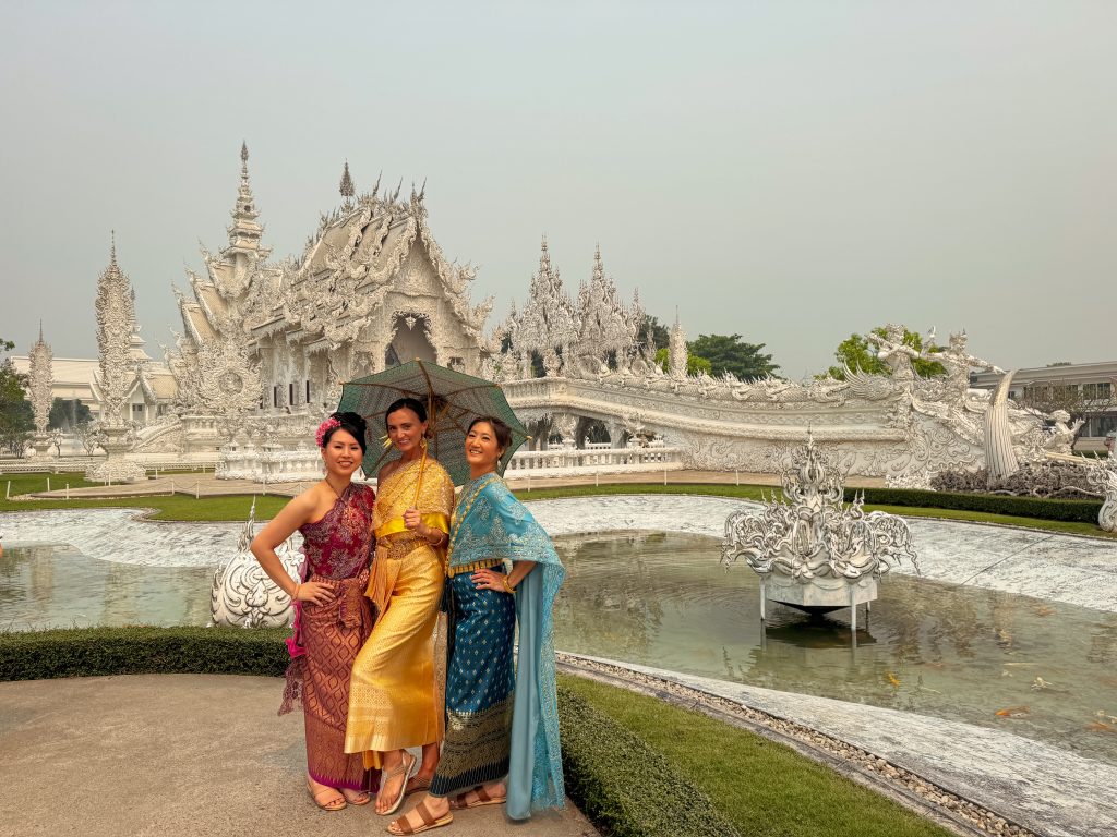 3 women in colorful Thai dresses in front of the White Temple