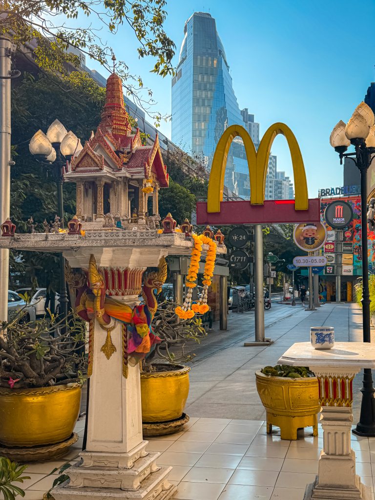 Buddhist shrine in front of McDonald's sign with sky scrappers behind