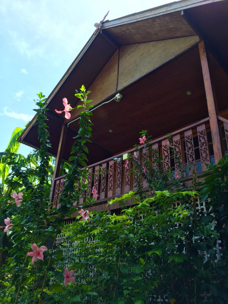 Flowers in front of a wooden bungalow with balcony