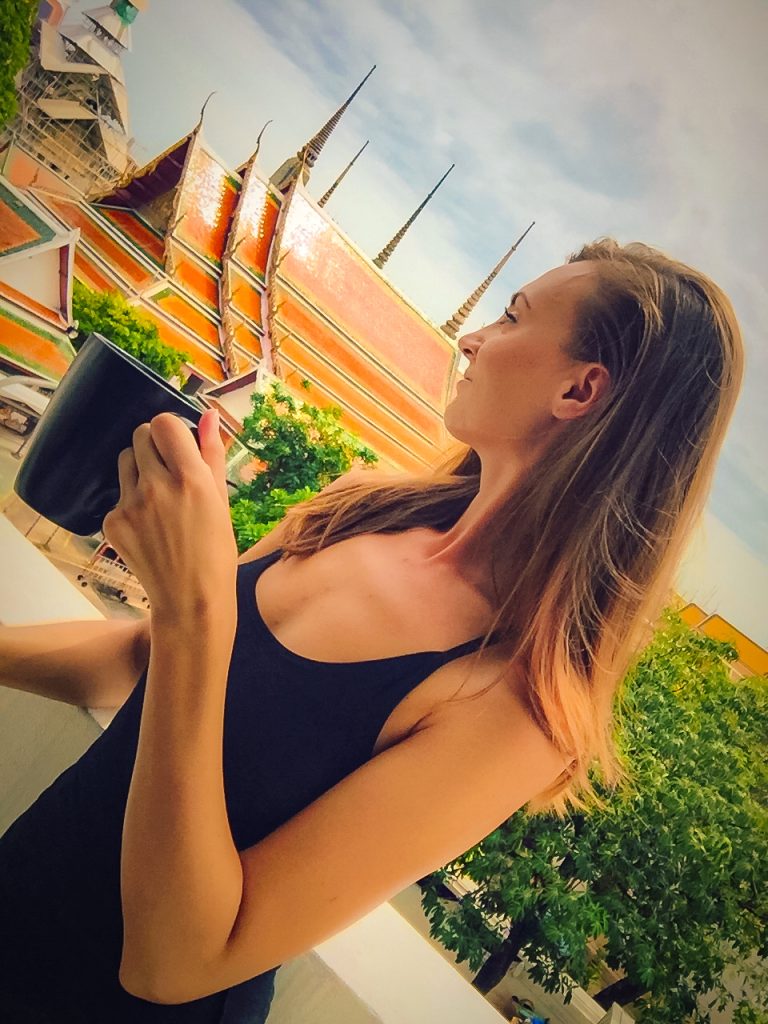 Woman drinking coffee with Thai temple behind her