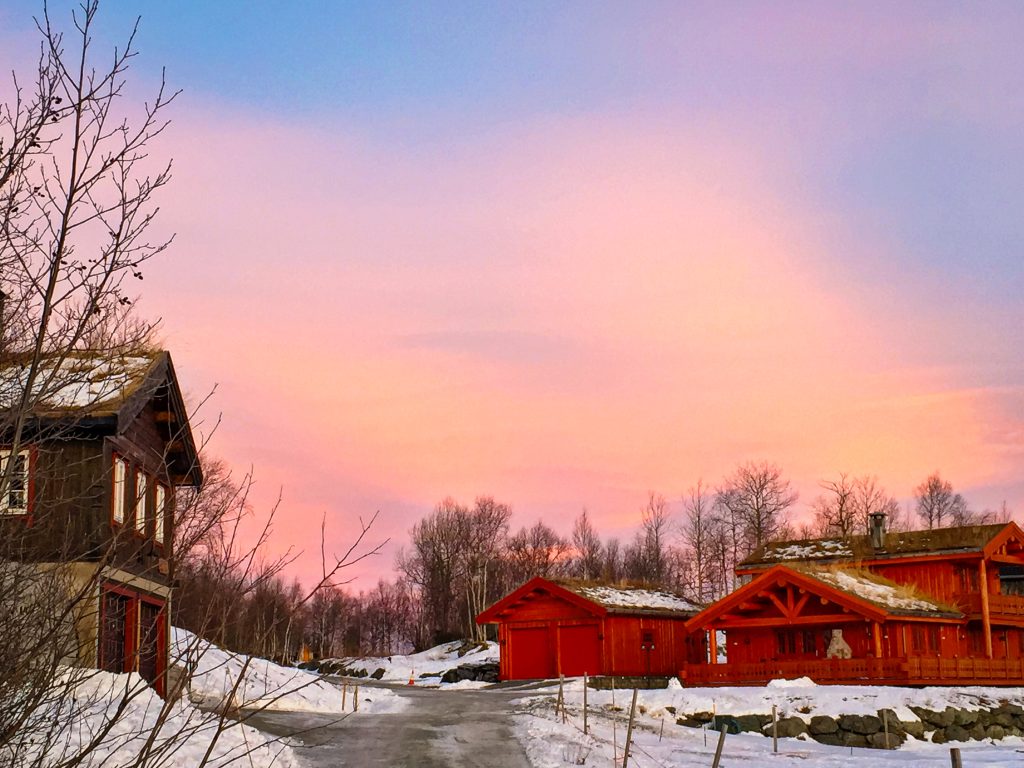 Snow covered cabins in Oppdal, Norway at sunset