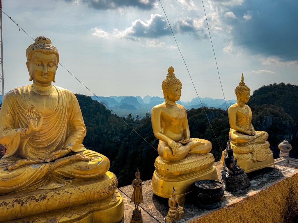 Golden Buddha statues facing the limestone mountain scenery from Tiger Cave Temple