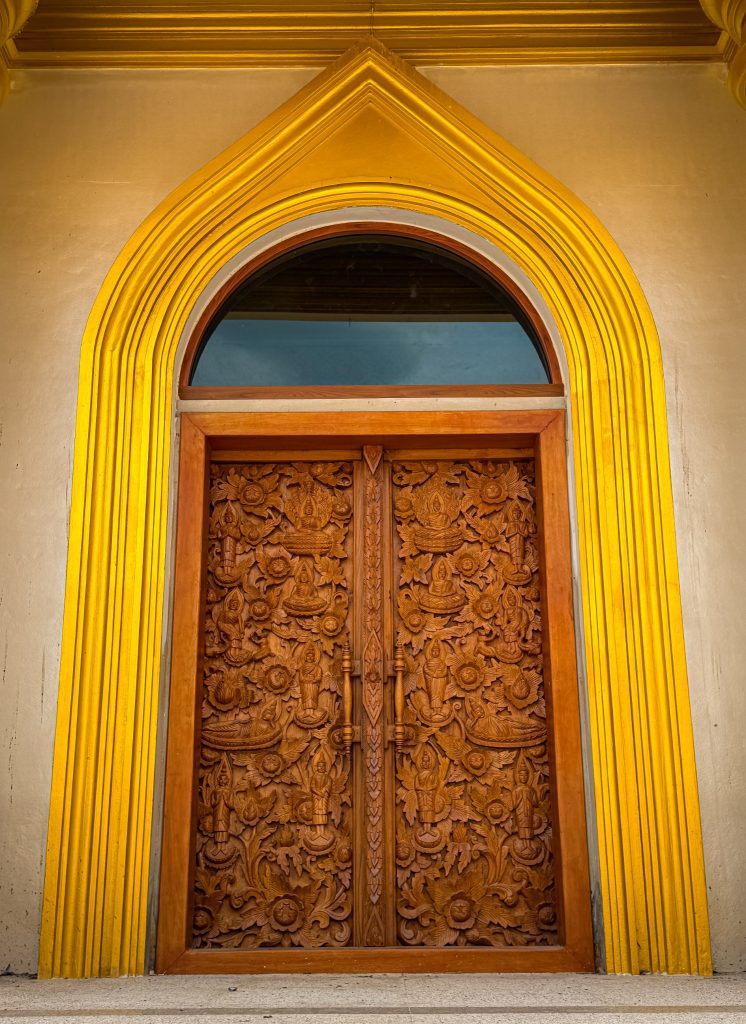 Intricately carved wooden door framed in gold at Tiger Cave Temple