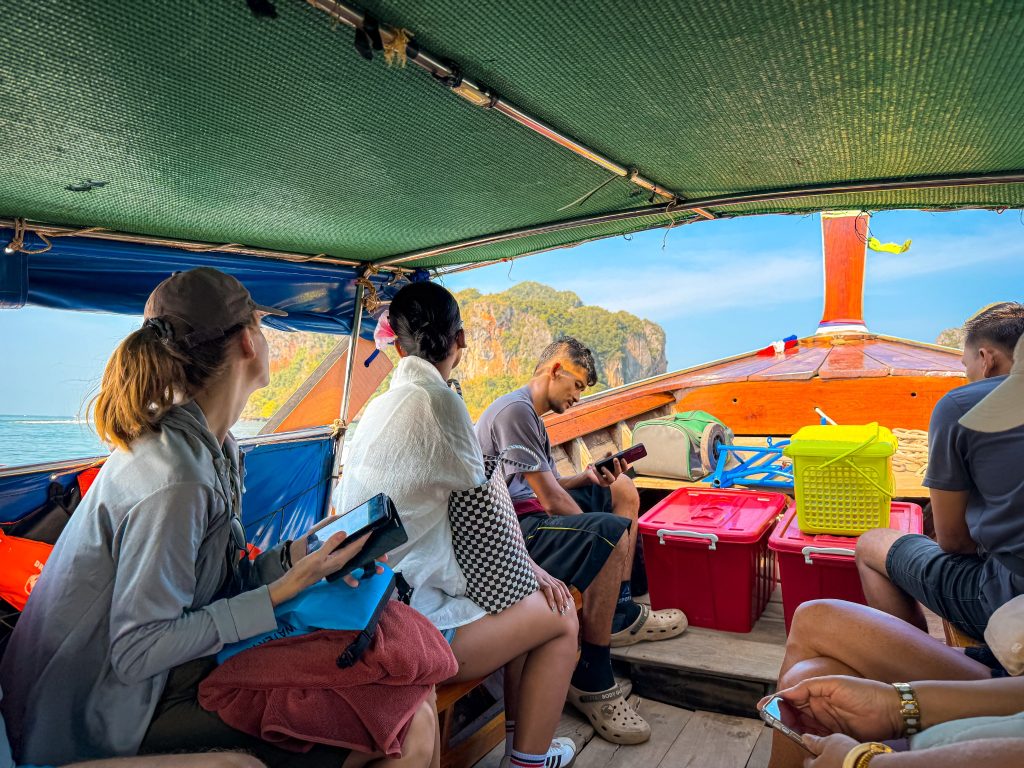 Passengers seated inside a traditional longtail boat traveling toward Railay Beach.