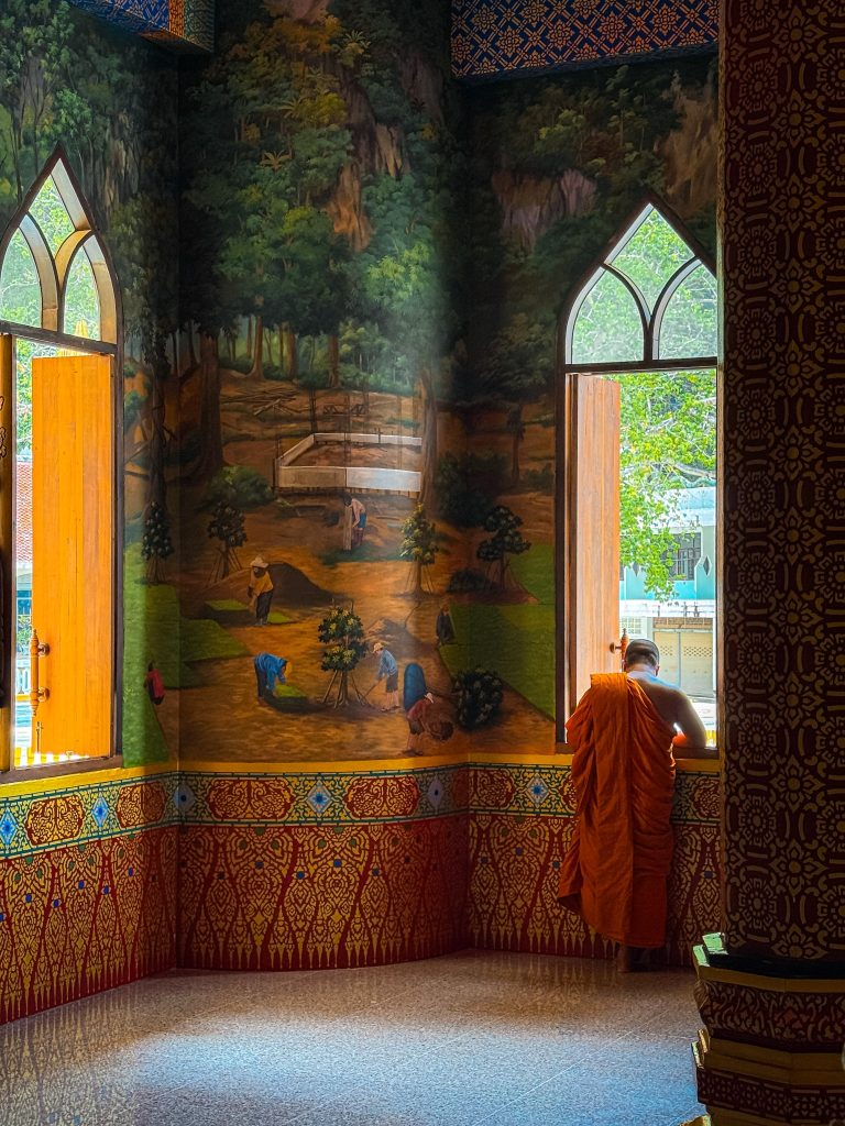 Buddhist monk standing by an open window inside Tiger Cave Temple