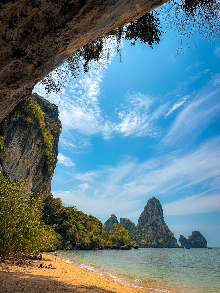 Tonsai Beach framed by limestone cliffs beneath a vivid blue sky with wispy clouds.