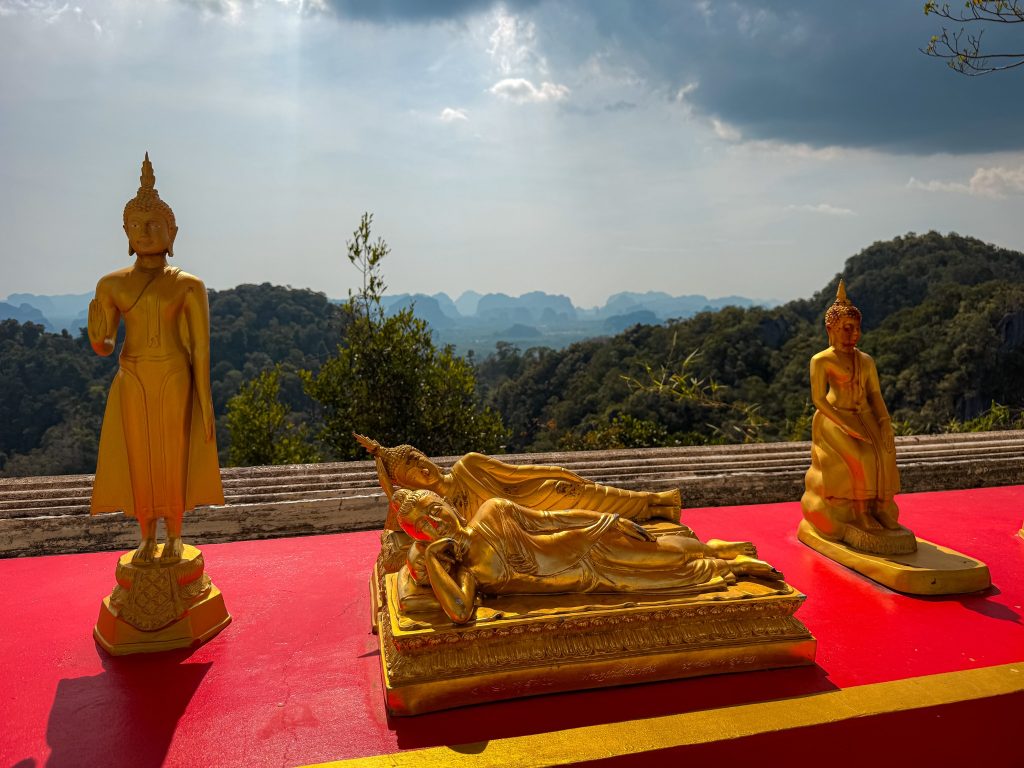 Golden reclining and standing Buddha statues with mountain views at Tiger Cave Temple