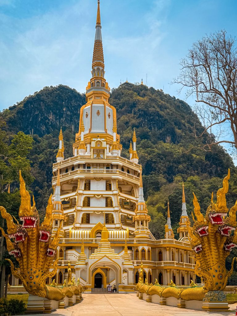 White and gold pagoda at Tiger Cave Temple beneath limestone cliffs