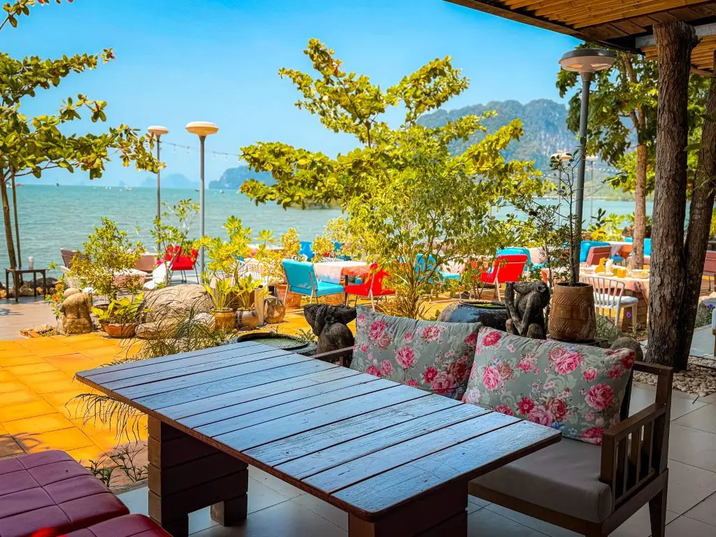 Colorful beachfront restaurant seating with sea and limestone cliff views at Villa Cha-Cha Krabi.