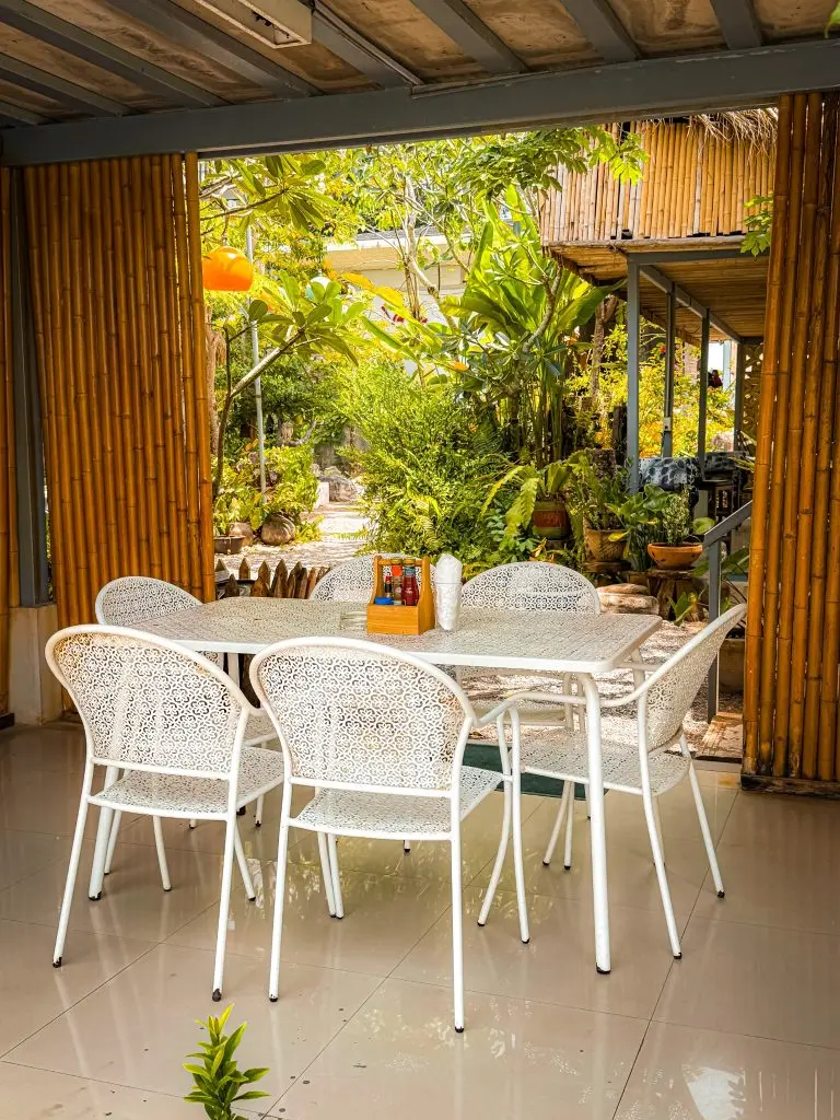 White metal dining table overlooking a lush garden at Villa Cha-Cha Krabi.