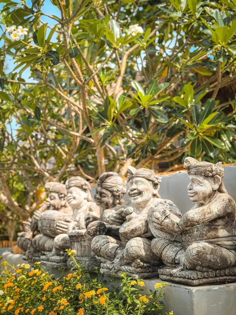 Close-up of traditional musician statues beneath tropical trees at Villa Cha-Cha Krabi.