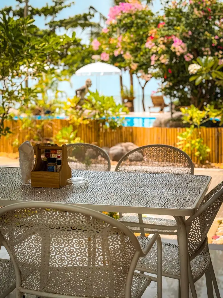 Outdoor dining table with a garden and swimming pool view at Villa Cha-Cha Krabi.