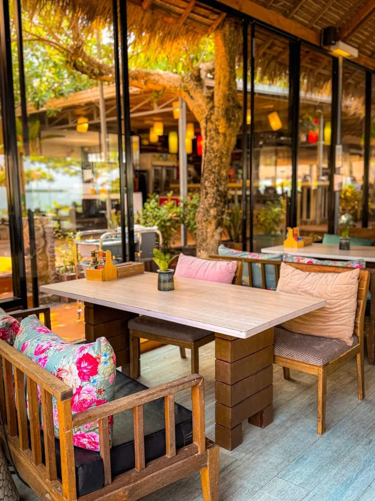 Wooden restaurant table with colorful cushions at Villa Cha-Cha Krabi Beachfront Resort.