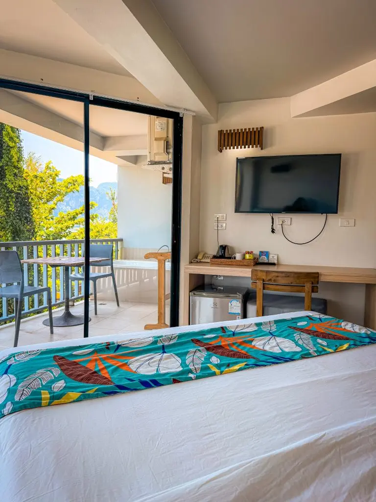 Villa Cha-Cha Krabi guest room with a balcony, television, desk, mini fridge, and partial limestone cliff view.