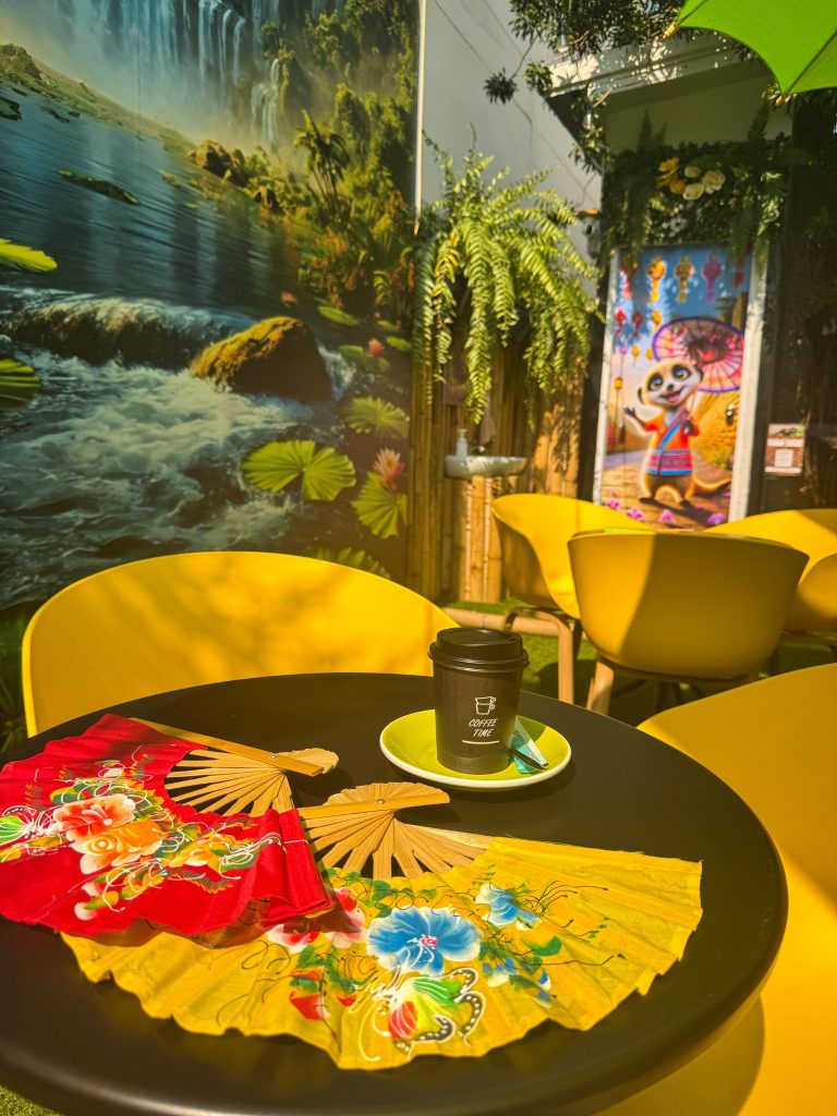 Coffee and colorful decorative fans on a table inside the animal area at Capybara Cafe Thailand.