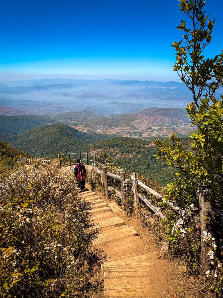 Hiker descending steps along the Kew Mae Pan Nature Trail overlooking the mountains of Doi Inthanon National Park.