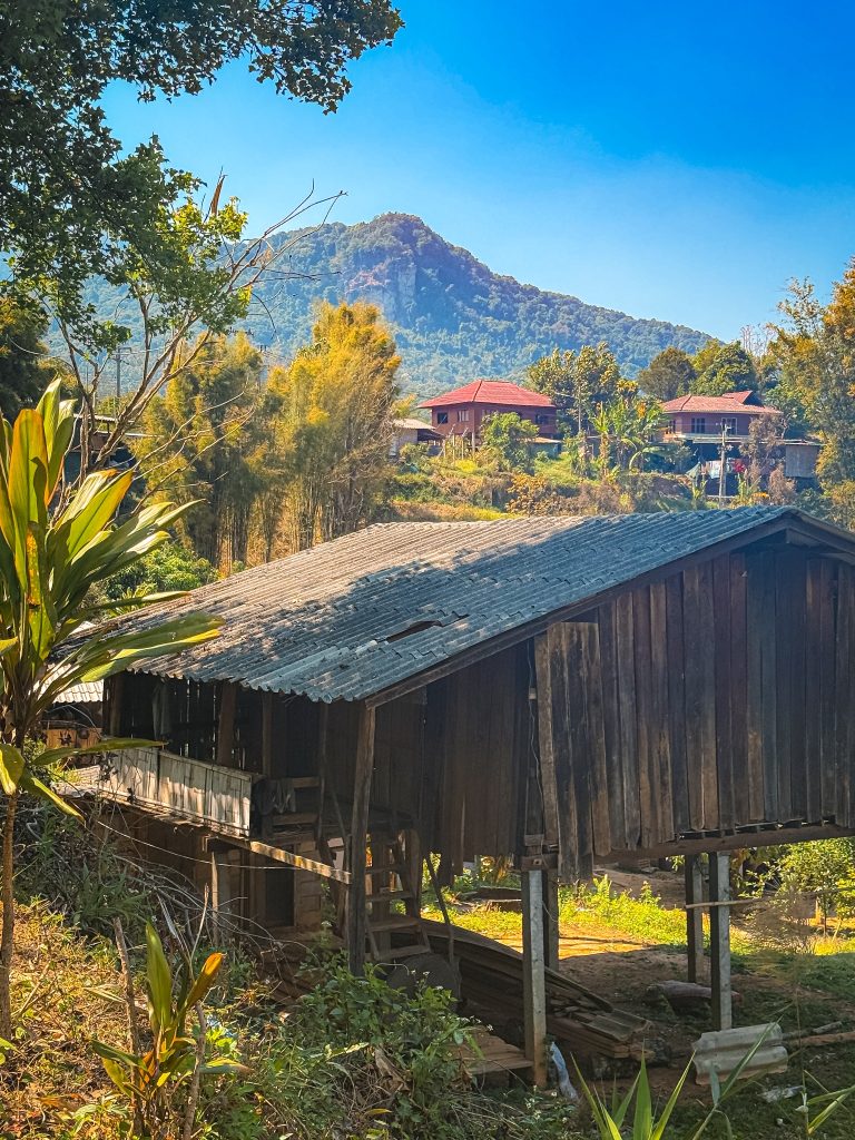 Traditional wooden Hmong village house surrounded by mountain scenery near Doi Inthanon National Park in northern Thailand.