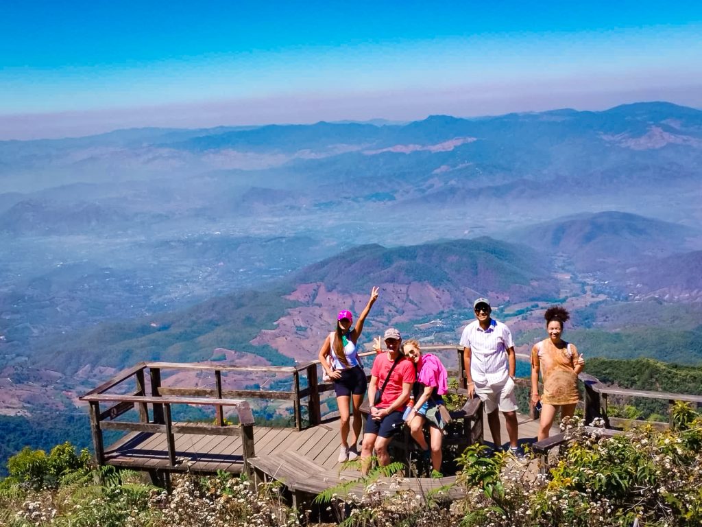 Group of travelers at a scenic Kew Mae Pan viewpoint overlooking the mountains of Doi Inthanon National Park.