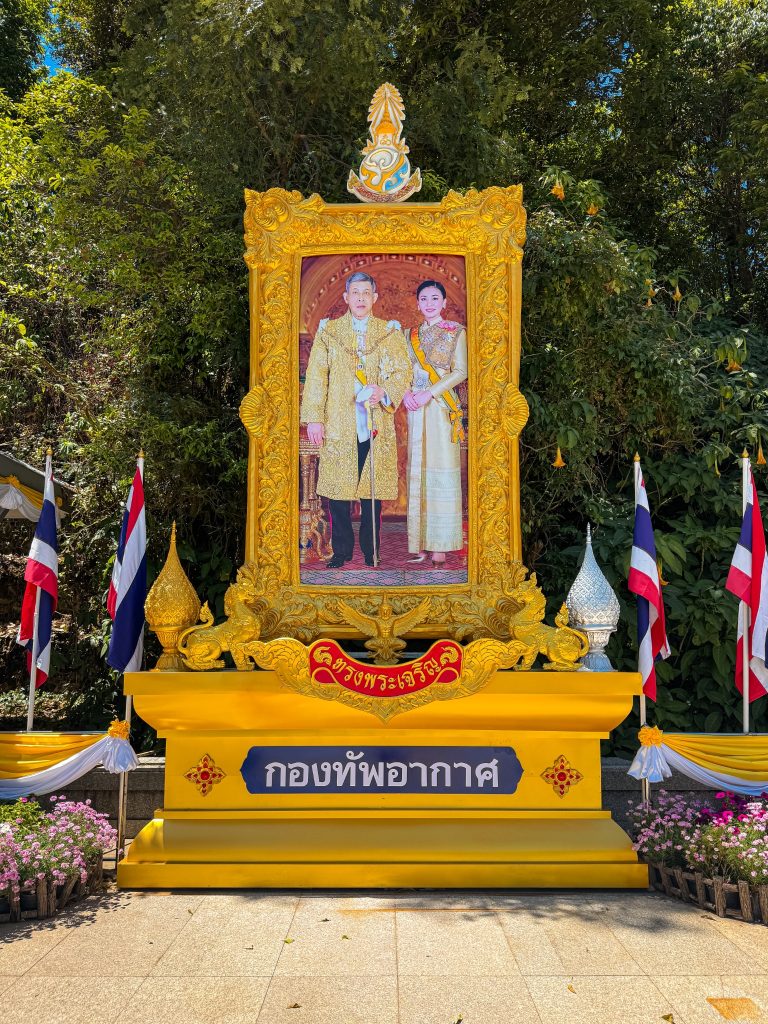 Ornate gold-framed royal portrait surrounded by Thai flags near the Royal Pagodas at Doi Inthanon National Park.