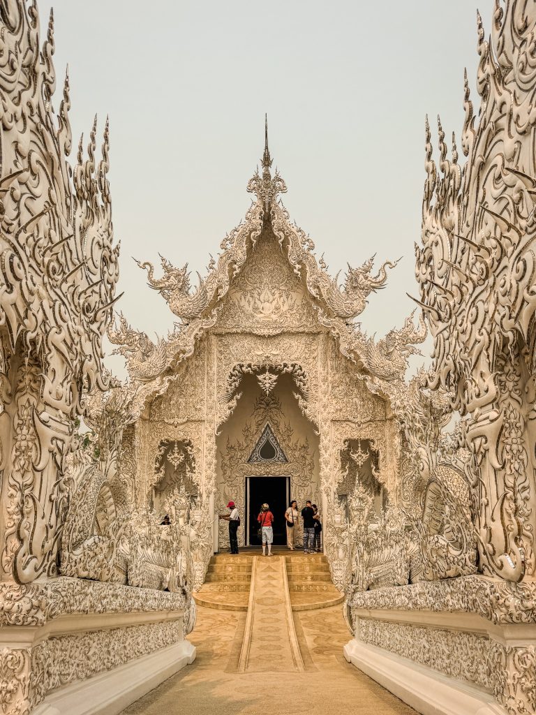 Front view of the ornate White Temple entrance framed by detailed white sculpted columns.