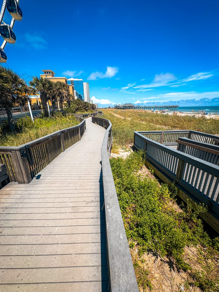 Winding Myrtle Beach boardwalk lined with palm trees and the beach next to it