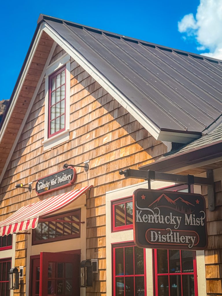Wooden shingle building with red and white trim windows with Kentucky Mist Distillery sign