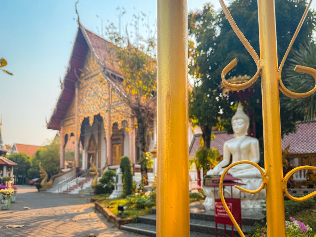 Buddha statue and ornate temple behind a gold gate