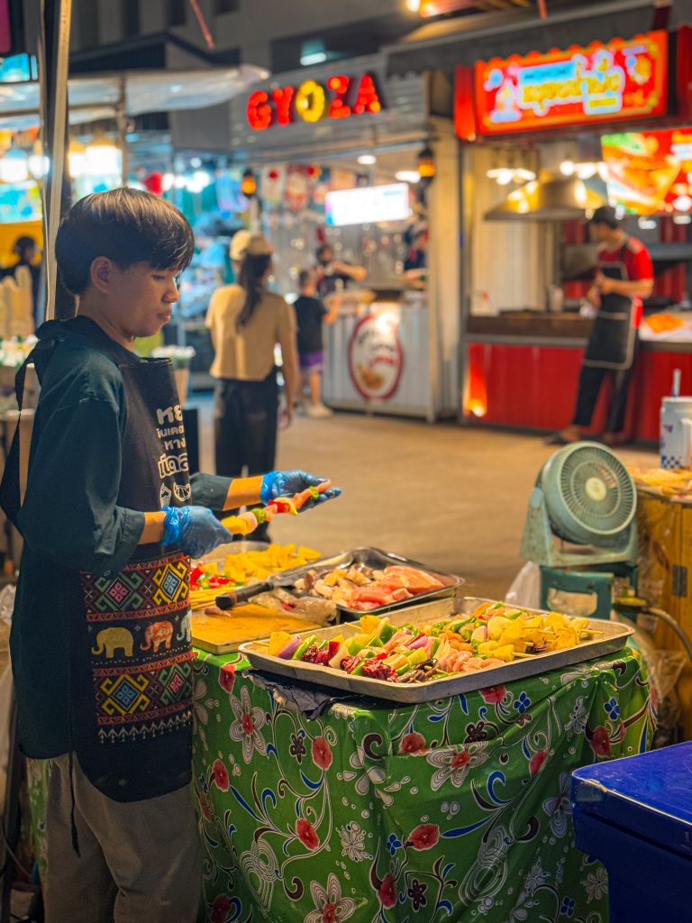Vendor at a night market making kabobs