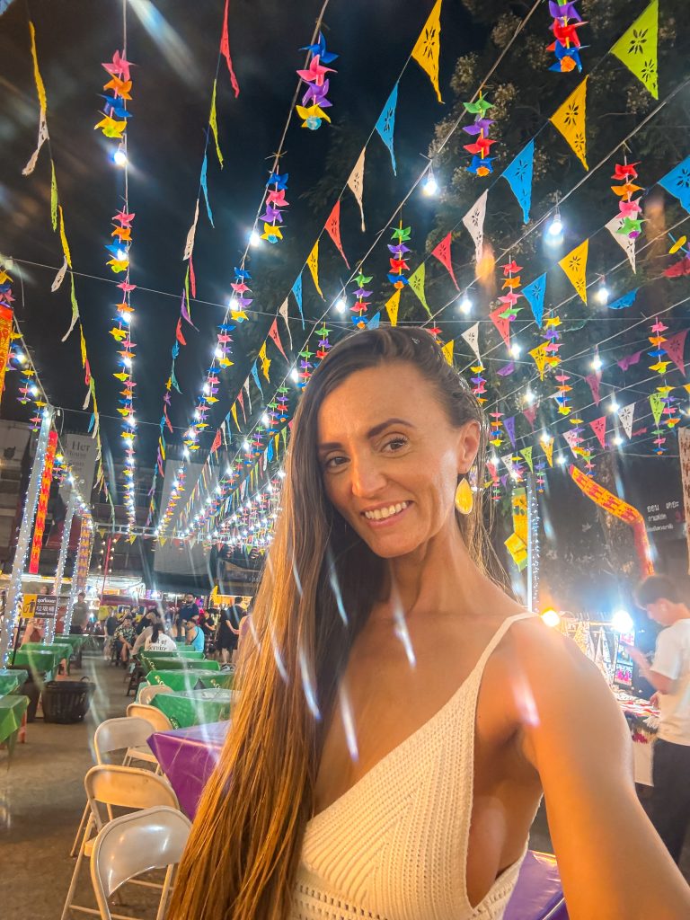 Smiling woman under flags at the Thai night market