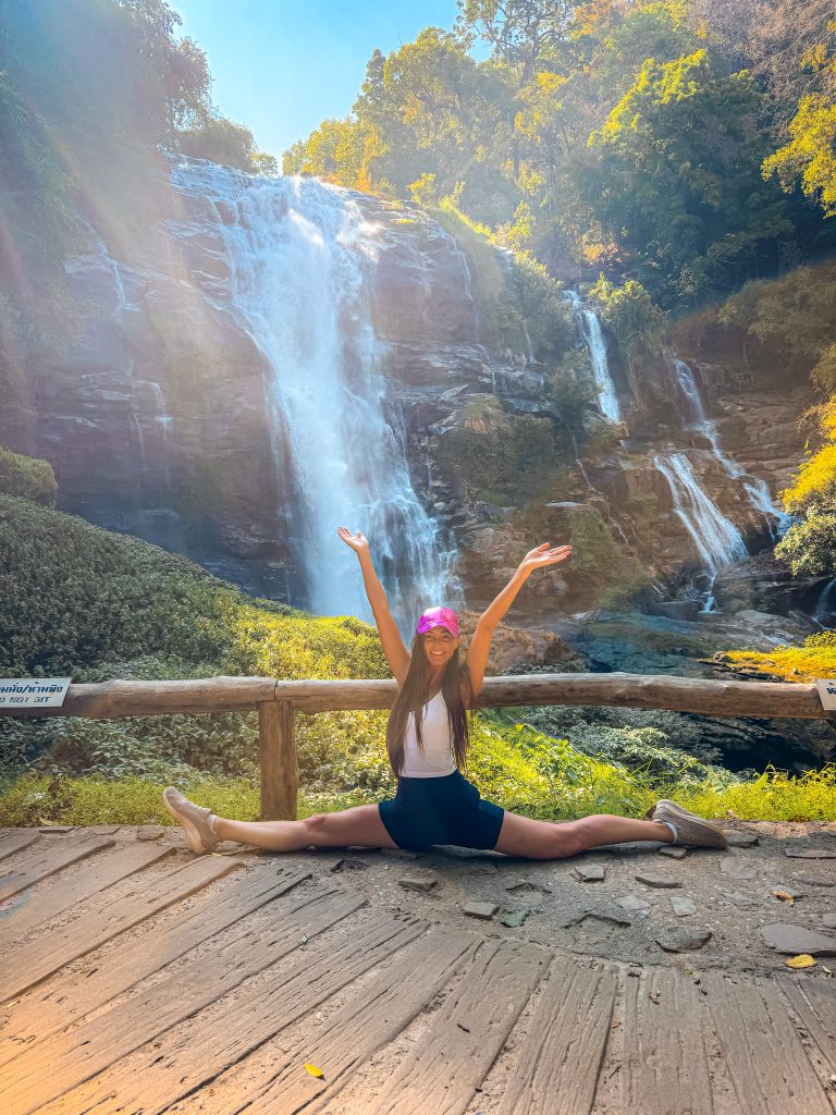 Woman doing the splits in front of a waterfall in Northern Thailand