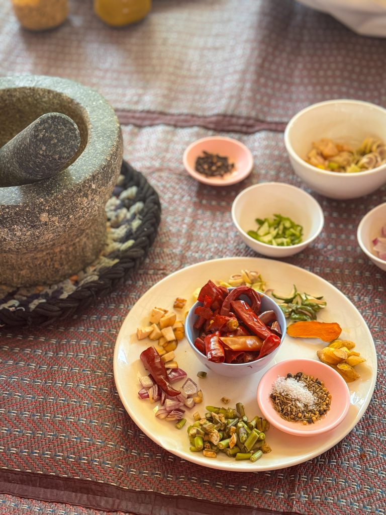 Dishes of many different spices next to a mortar and pestle