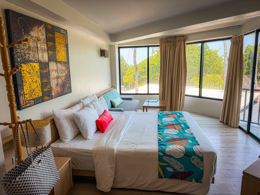 Hotel bed and couch with bright windows lining the room