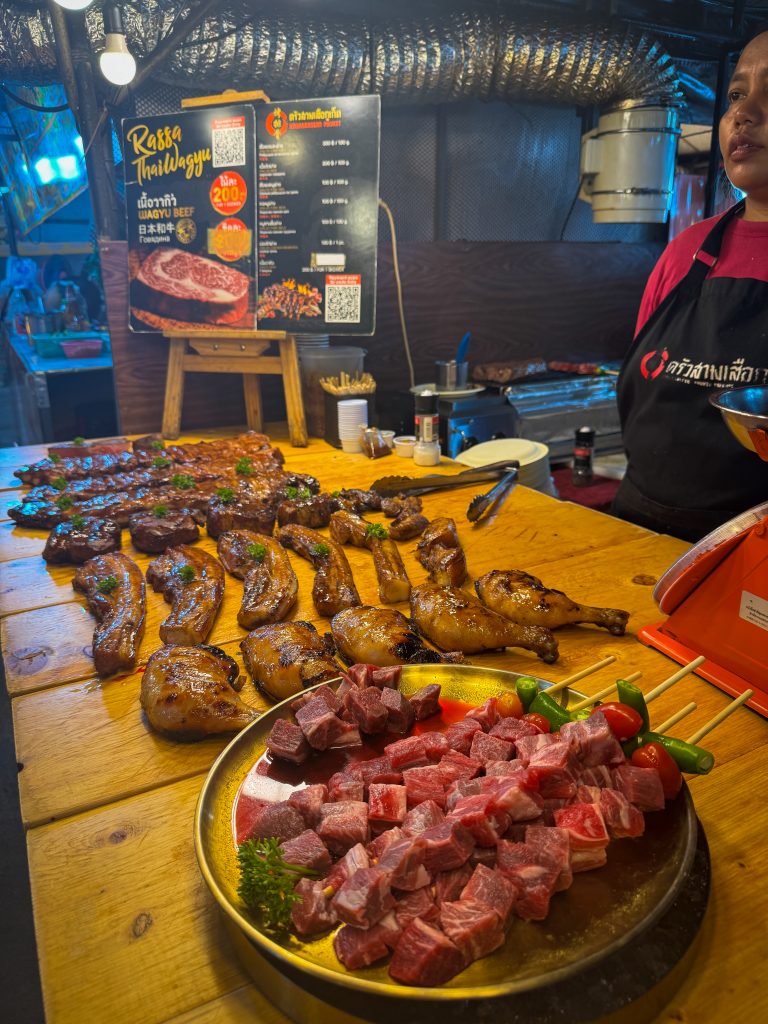 Rows of grilled meats on skewers at a night market in Thailand