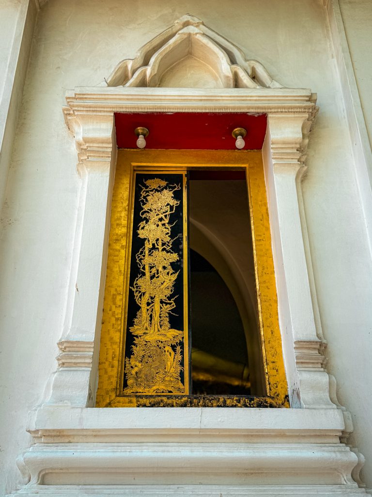 Carved window with gold decorative shutters on Thai temple