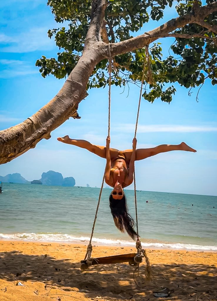 Woman hanging upside down on beach swing