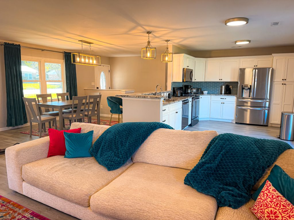 A couch with full kitchen and dining room behind it in an Airbnb