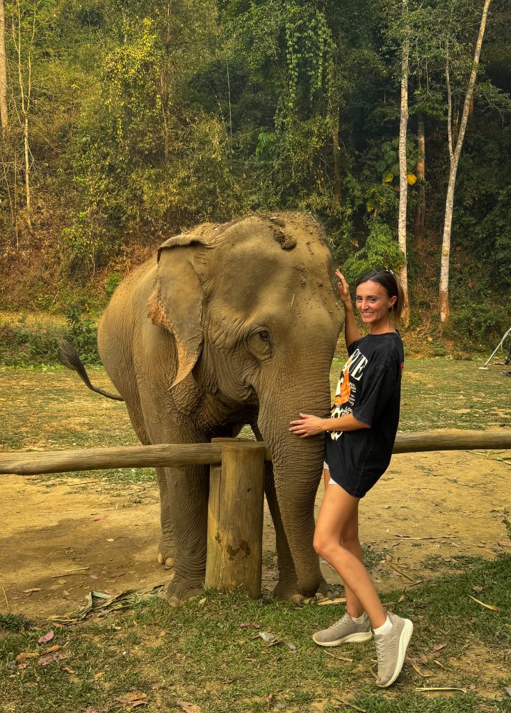 Woman standing close to Thai elephant