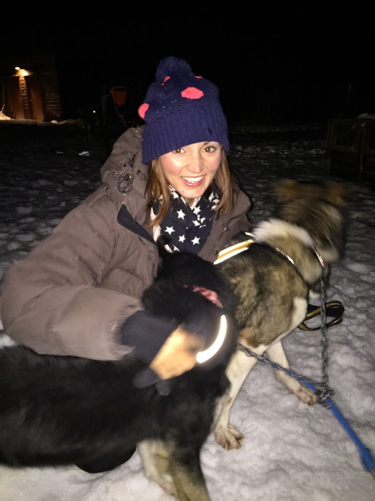 Woman hugging 2 dog sled dogs