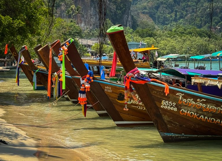 Row of wooden longtail boats with colorful adornments in Railay Beach
