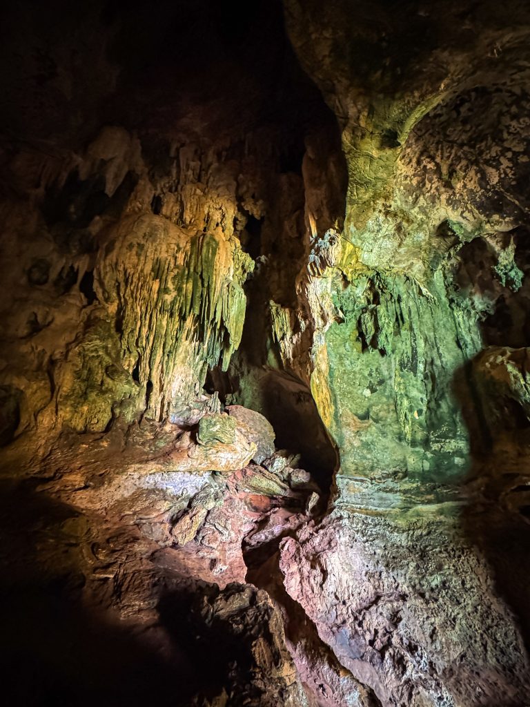 Stalactites and textured limestone formations illuminated inside Bat Cave in Railay.