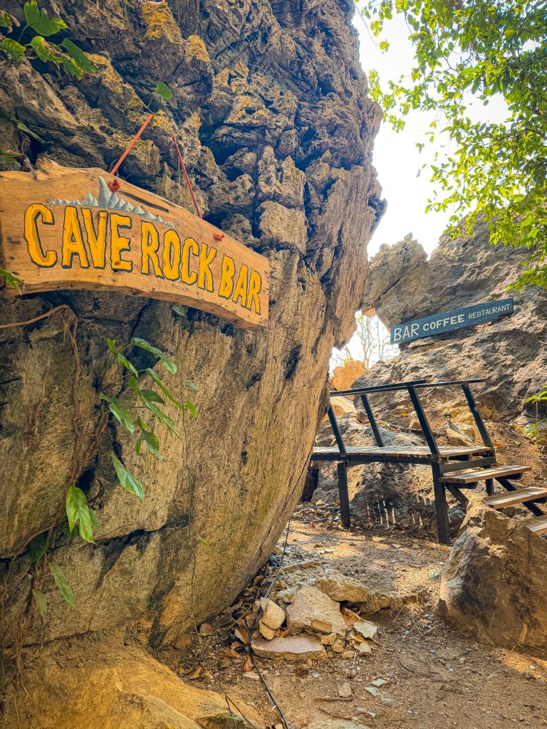 Wooden Cave Rock Bar sign hanging beside a rocky staircase at Railay East.