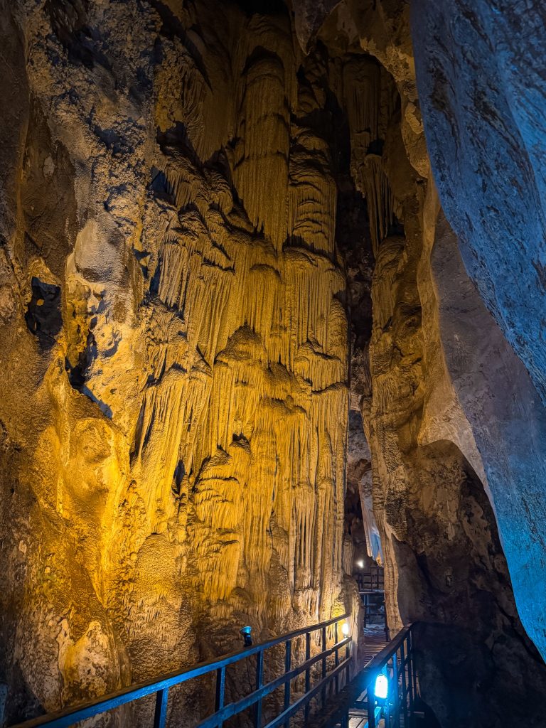 Large illuminated stalactite formations beside the walkway inside Diamond Cave in Railay.